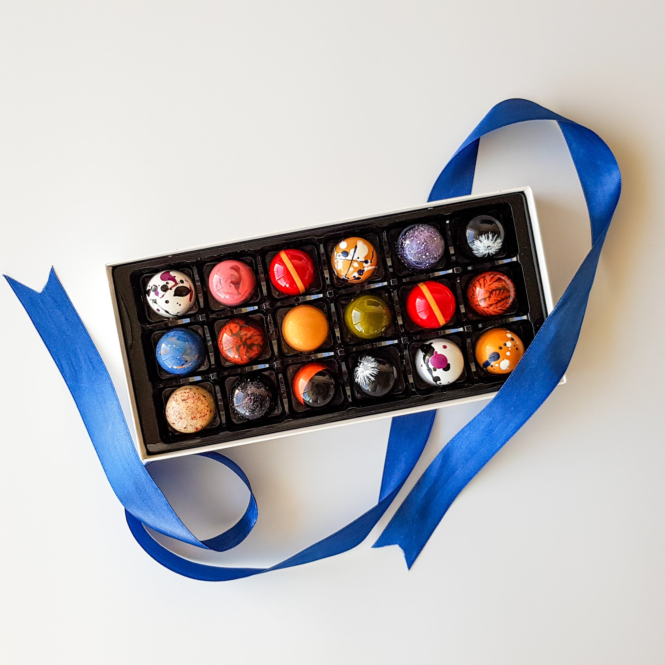 Box of 18 coloured chocolate bonbon pralines with blue ribbon