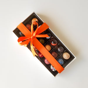 Box of 18 coloured chocolate bonbon pralines wrapped in orange ribbon